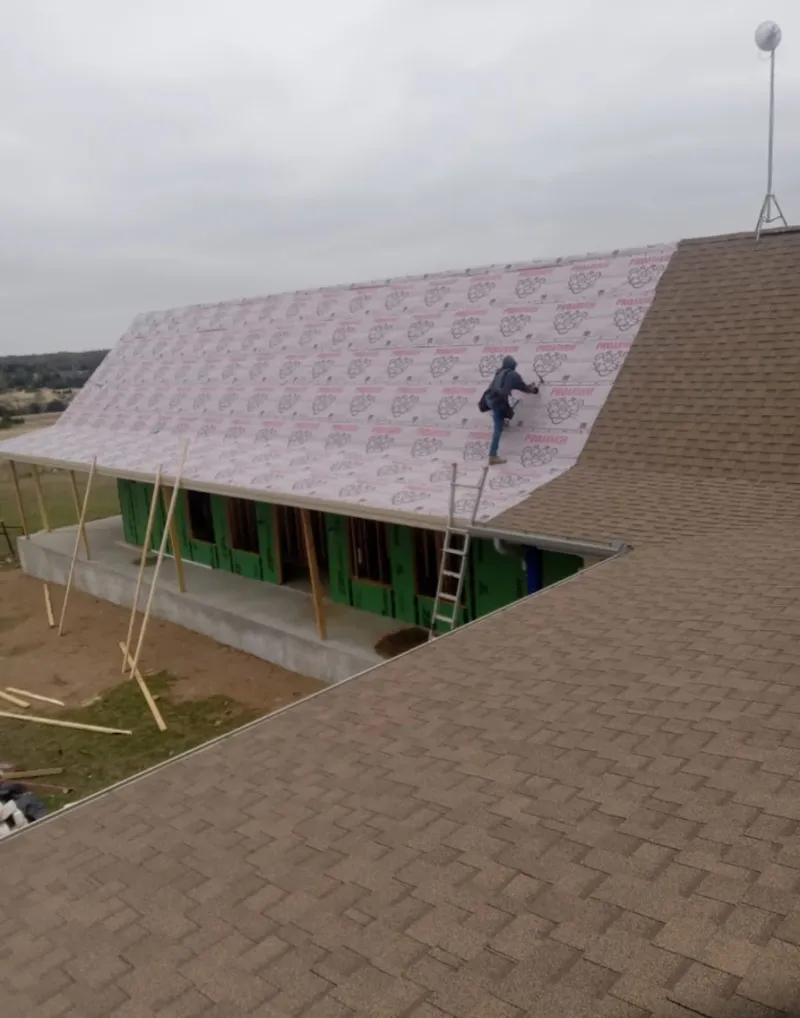 Worker preparing underlayment for a metal roof installation in Oatfield